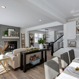 Mittelgroßes, Fernseherloses, Offenes Landhaus Wohnzimmer mit weißer Wandfarbe, Laminat, Kamin, gefliester Kaminumrandung und grauem Boden in Minneapolis