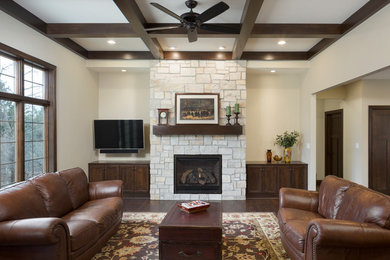 Large arts and crafts dark wood floor, brown floor and coffered ceiling living room photo in Milwaukee with beige walls, a standard fireplace, a stone fireplace and a wall-mounted tv
