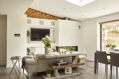 This is an example of a modern open plan living room in Essex with white walls, porcelain flooring, a corner fireplace, a plastered fireplace surround, a wall mounted tv and grey floors.