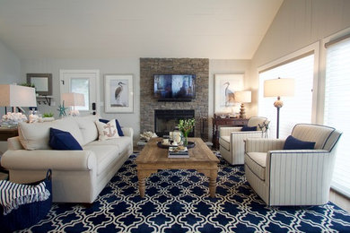 Стильный дизайн: открытая гостиная комната среднего размера в морском стиле с серыми стенами, полом из керамогранита, стандартным камином, фасадом камина из камня, телевизором на стене и бежевым полом - последний тренд