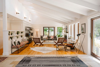 Inspiration for a transitional formal and open concept medium tone wood floor, brown floor, exposed beam and vaulted ceiling living room remodel in San Francisco with white walls, a standard fireplace, a stone fireplace and no tv