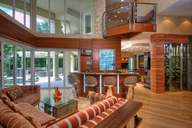 Mittelgroßes, Offenes Modernes Wohnzimmer mit Hausbar, brauner Wandfarbe, hellem Holzboden und Multimediawand in Tampa
