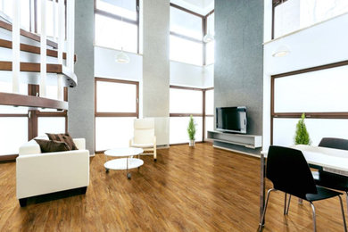 Cette photo montre un grand salon tendance ouvert avec un mur gris, parquet foncé, un téléviseur indépendant et un sol marron.