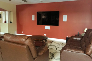 Diseño de salón sin chimenea con paredes rojas, moqueta y televisor colgado en la pared