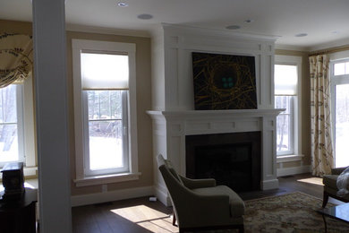 На фото: гостиная комната с белыми стенами, паркетным полом среднего тона, стандартным камином и фасадом камина из штукатурки без телевизора с