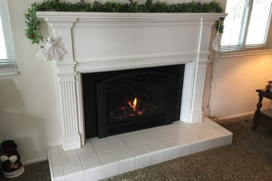 ソルトレイクシティにあるお手頃価格の中くらいなトラディショナルスタイルのおしゃれなリビング (白い壁、カーペット敷き、標準型暖炉、木材の暖炉まわり、テレビなし、茶色い床) の写真