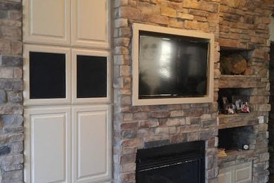 フェニックスにある広いラスティックスタイルのおしゃれなLDK (茶色い壁、無垢フローリング、標準型暖炉、石材の暖炉まわり、壁掛け型テレビ、茶色い床) の写真