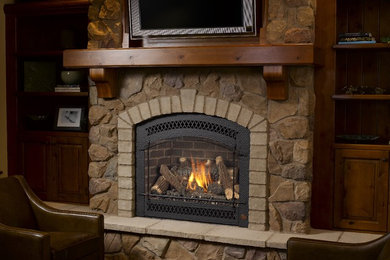 Rustic living room in San Luis Obispo with dark hardwood flooring, a stone fireplace surround and a standard fireplace.