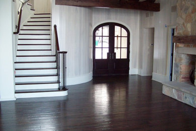 Imagen de salón de estilo americano con suelo de madera oscura, chimeneas suspendidas y marco de chimenea de piedra