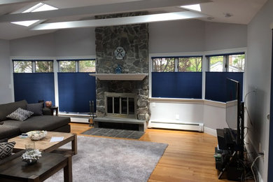 Example of a large classic formal and enclosed light wood floor and brown floor living room design in New York with gray walls, a standard fireplace, a stone fireplace and a tv stand