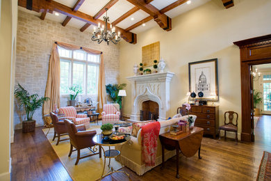 Cette image montre un grand salon traditionnel fermé avec une salle de réception, un mur blanc, un sol en bois brun, une cheminée standard, un manteau de cheminée en pierre et un sol marron.