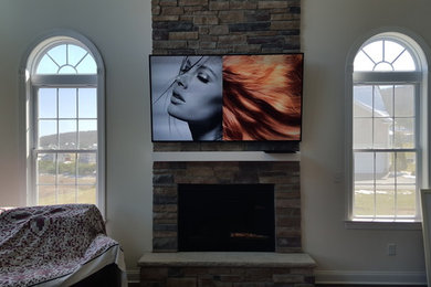 Example of a large classic formal and enclosed dark wood floor and brown floor living room design in Providence with beige walls, a standard fireplace, a stone fireplace and a wall-mounted tv