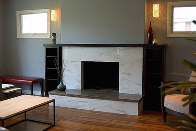 サンディエゴにある中くらいなトランジショナルスタイルのおしゃれなLDK (グレーの壁、標準型暖炉、石材の暖炉まわり、茶色い床、無垢フローリング) の写真