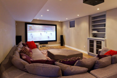Home theater - mid-sized traditional enclosed medium tone wood floor home theater idea in New York with beige walls and a wall-mounted tv