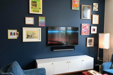 Diseño de salón para visitas cerrado bohemio de tamaño medio sin chimenea con paredes azules, suelo de madera en tonos medios, televisor colgado en la pared y suelo marrón