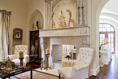 Ejemplo de salón para visitas tradicional renovado de tamaño medio con paredes blancas, suelo de madera oscura, chimenea de doble cara, marco de chimenea de yeso y suelo marrón