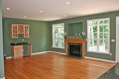 Ejemplo de salón abierto clásico grande con suelo de madera en tonos medios, paredes verdes y todas las chimeneas