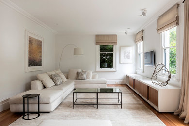 Foto di un grande soggiorno minimal aperto con sala formale, pareti bianche, parquet chiaro, TV a parete e nessun camino