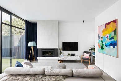 Diseño de salón actual con paredes blancas, suelo de cemento, todas las chimeneas, televisor colgado en la pared y suelo gris