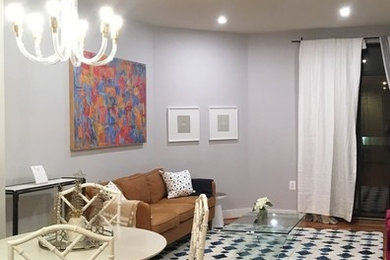 Modelo de salón abierto actual de tamaño medio sin chimenea y televisor con paredes púrpuras, suelo de madera en tonos medios y suelo marrón