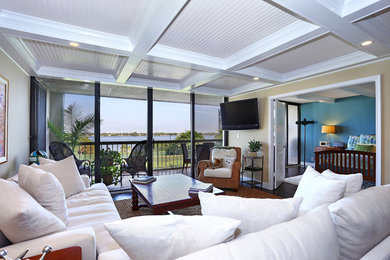 Maritimes Wohnzimmer mit beiger Wandfarbe, braunem Holzboden und TV-Wand in Miami