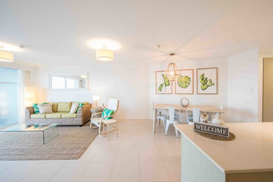 Immagine di un piccolo soggiorno costiero aperto con pareti bianche, pavimento con piastrelle in ceramica, TV a parete e pavimento beige