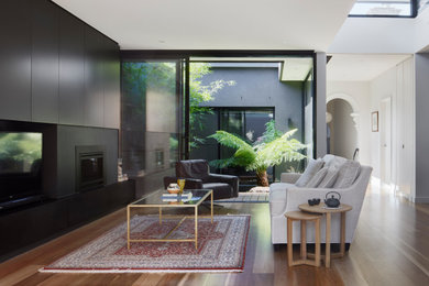 Стильный дизайн: открытая гостиная комната среднего размера в современном стиле с белыми стенами, паркетным полом среднего тона, стандартным камином, фасадом камина из металла и телевизором на стене - последний тренд