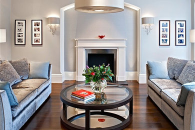 Example of a transitional brown floor living room design in London with gray walls and a standard fireplace