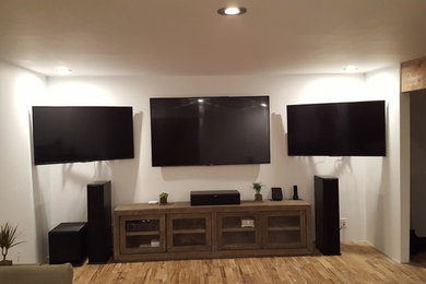 Imagen de salón actual de tamaño medio sin chimenea con paredes blancas, suelo de madera en tonos medios, televisor colgado en la pared y suelo marrón