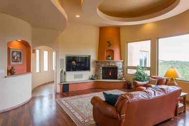 Mid-sized southwest open concept dark wood floor living room photo in Albuquerque with beige walls, a standard fireplace, a stone fireplace and a wall-mounted tv