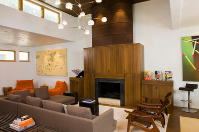 Стильный дизайн: гостиная комната в современном стиле с белыми стенами, темным паркетным полом, стандартным камином и фасадом камина из дерева - последний тренд