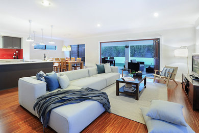 Cette image montre un grand salon minimaliste ouvert avec un mur blanc, parquet en bambou, aucune cheminée, un téléviseur indépendant et un sol marron.