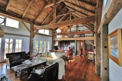 Aménagement d'un salon classique ouvert avec un mur blanc, un sol en bois brun, une cheminée standard et un manteau de cheminée en pierre.