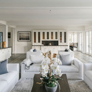 Idee per un ampio soggiorno stile marinaro aperto con sala formale, pareti bianche, pavimento in compensato, camino classico, cornice del camino in pietra e pavimento bianco