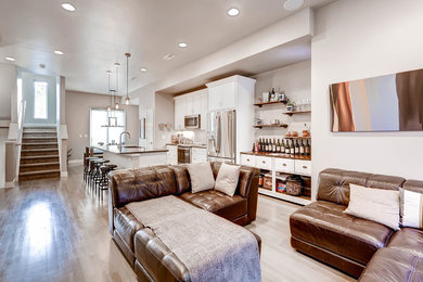 Imagen de salón abierto minimalista de tamaño medio con paredes grises, televisor colgado en la pared, suelo de madera clara y suelo marrón