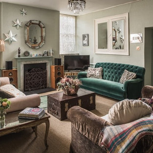 Medium sized living room in Other with green walls, carpet, a standard fireplace, a freestanding tv and brown floors.