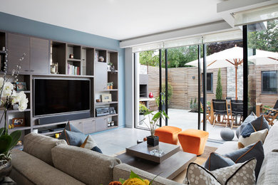 Contemporary living room in London with blue walls, a wall mounted tv and grey floors.
