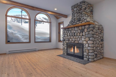 バンクーバーにあるお手頃価格の中くらいなラスティックスタイルのおしゃれなLDK (白い壁、淡色無垢フローリング、標準型暖炉、石材の暖炉まわり、茶色い床) の写真