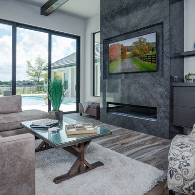 Inspiration for a large contemporary open concept porcelain tile and multicolored floor living room remodel in Tampa with gray walls, a standard fireplace, a tile fireplace and a wall-mounted tv