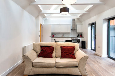 Trendy medium tone wood floor living room photo in London with white walls