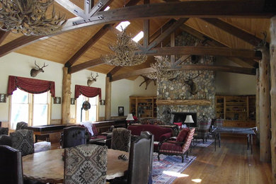 Modelo de salón rural extra grande sin televisor con paredes beige, suelo de madera en tonos medios, todas las chimeneas y marco de chimenea de madera