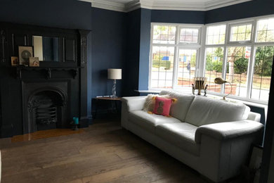 Inspiration for a traditional living room in London with blue walls, medium hardwood flooring, a standard fireplace and a wooden fireplace surround.