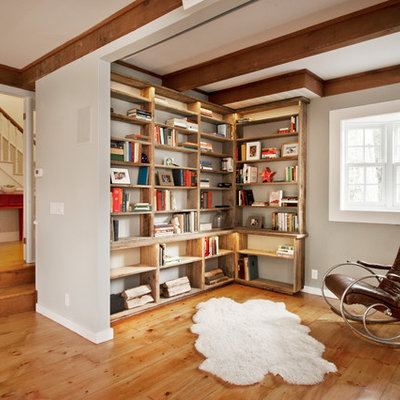 Example of a farmhouse medium tone wood floor living room library design in New York with gray walls