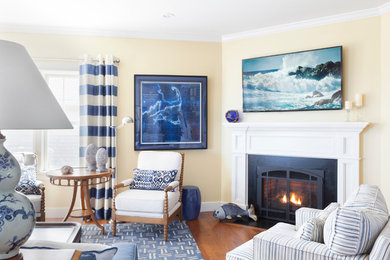 Inspiration for a mid-sized coastal formal and open concept medium tone wood floor and brown floor living room remodel in Boston with yellow walls, a corner fireplace, a wood fireplace surround and no tv