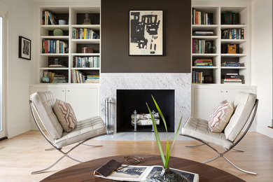 Example of a mid-sized trendy light wood floor living room library design in Portland Maine with multicolored walls and a standard fireplace