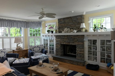 Example of a mid-sized cottage formal and enclosed light wood floor and beige floor living room design in New York with yellow walls, a standard fireplace, a stone fireplace and no tv