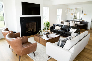 トロントにある広いトランジショナルスタイルのおしゃれなLDK (白い壁、淡色無垢フローリング、標準型暖炉、石材の暖炉まわり、壁掛け型テレビ、茶色い床) の写真