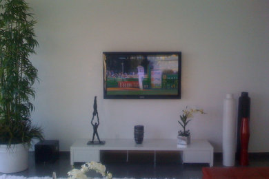 Modelo de salón moderno sin chimenea con paredes blancas y televisor colgado en la pared