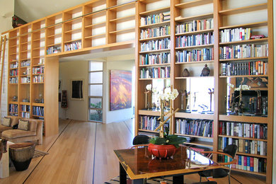 Modelo de biblioteca en casa abierta contemporánea grande con paredes blancas y suelo de madera en tonos medios