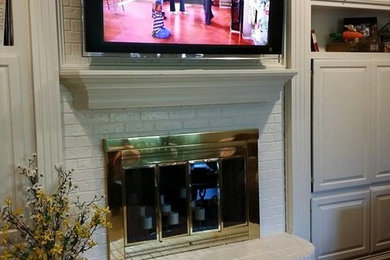 ダラスにあるトラディショナルスタイルのおしゃれなリビング (濃色無垢フローリング、標準型暖炉、レンガの暖炉まわり、壁掛け型テレビ) の写真